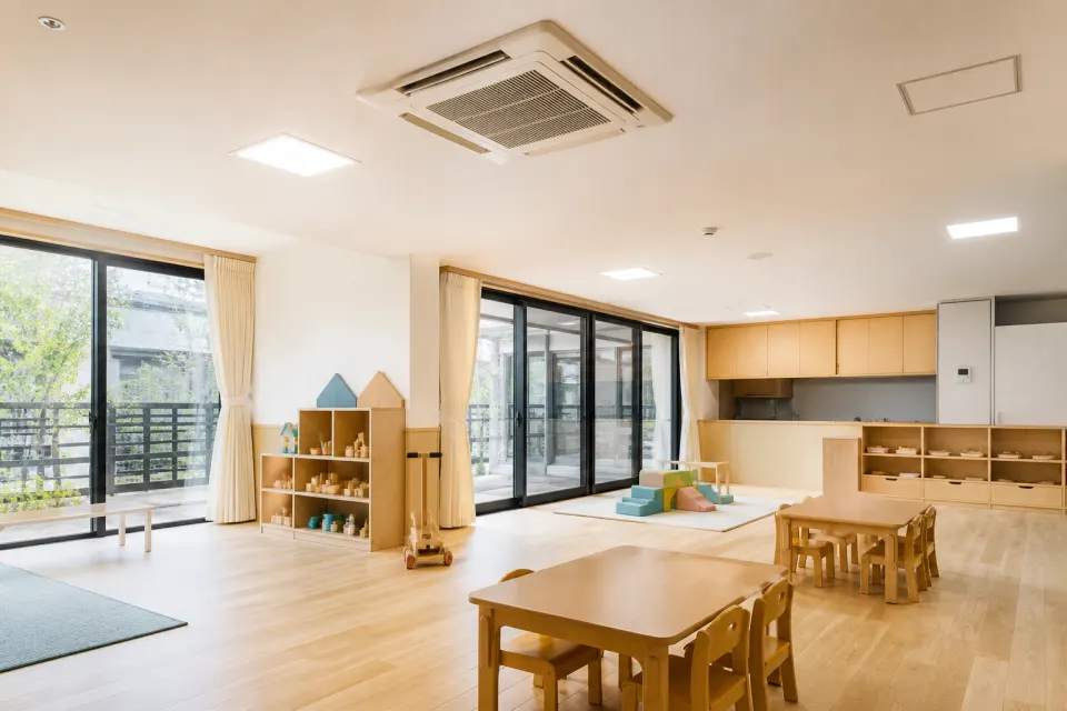 小さな机や椅子と遊具を備えた明るい保育施設の室内